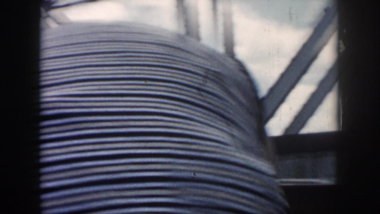 1958 New Orleans home-movie frame showing a man in a striped shirt viewed from behind inside a boat.