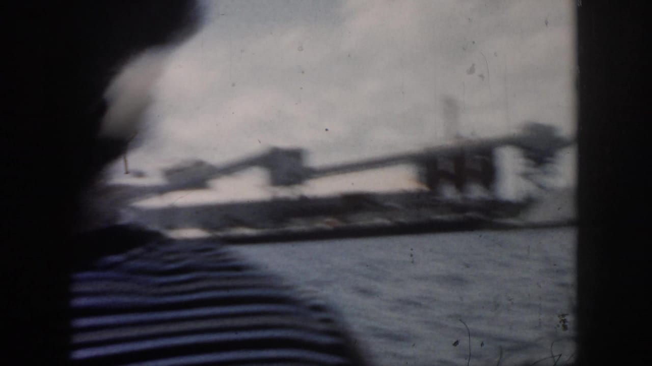 Foreground passenger in a striped shirt with water and shoreline beyond.