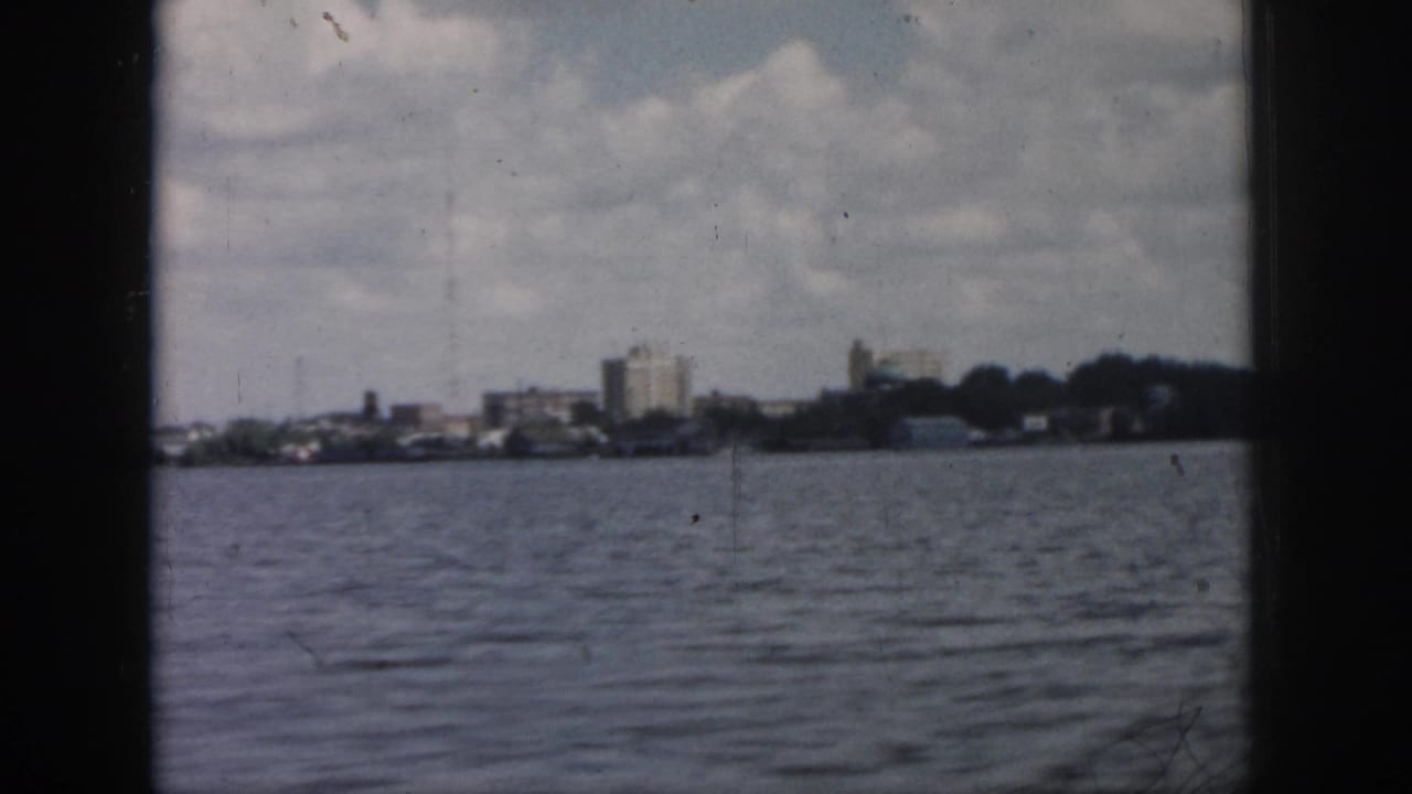 Waterfront skyline remains distant across choppy water with dark vertical framing at the sides.