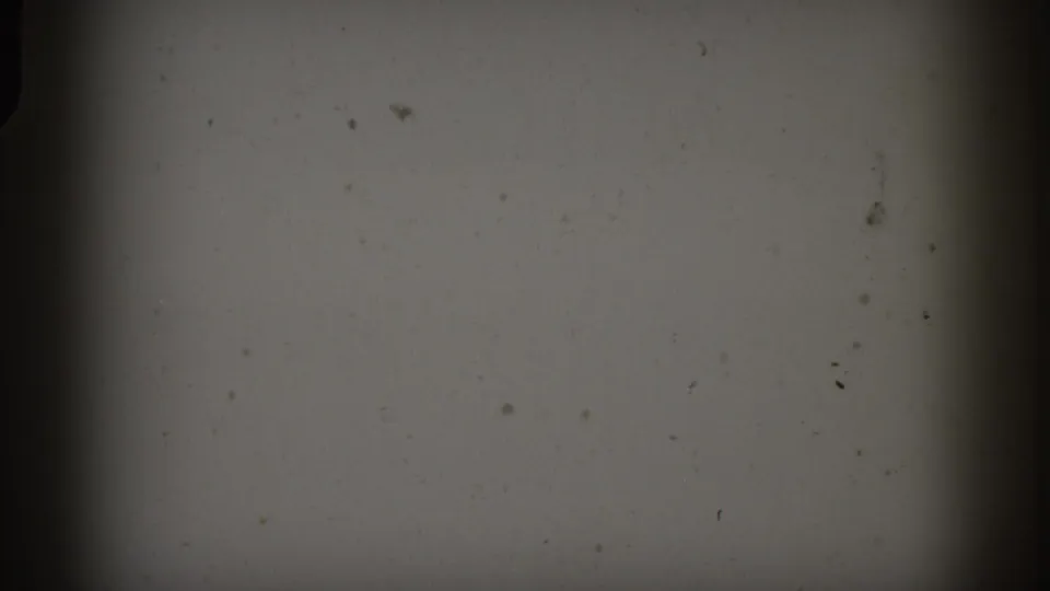 Opening frame shows pale exposed film area with visible dust, grain, and heavy dark masking before the parade view appears.