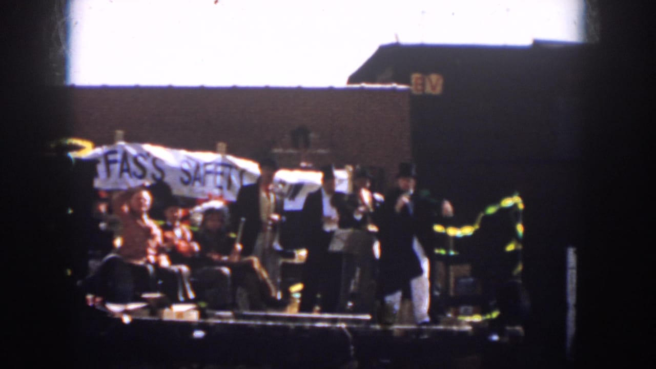 Home-movie frame from 1958 Virginia showing parade participants on a trailer with the FAS'S SAFETY text partly visible.