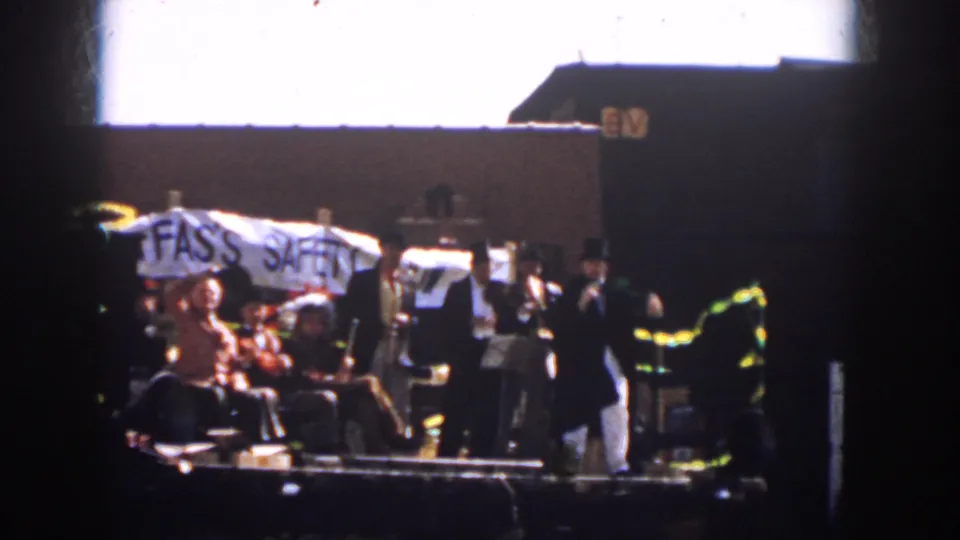 Home-movie frame from 1958 Virginia showing parade participants on a trailer with the FAS'S SAFETY text partly visible.