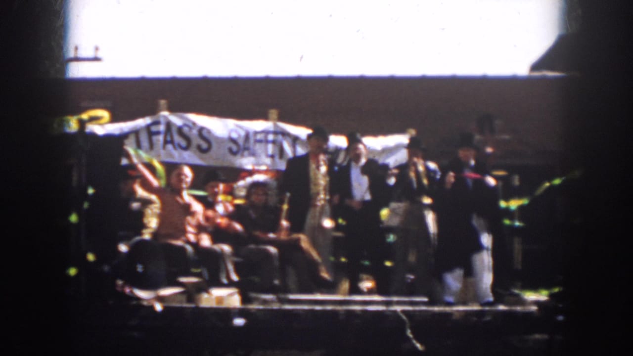 1958 Virginia parade frame with people on a flatbed trailer, dark-suited men, and a large FAS'S SAFETY banner.