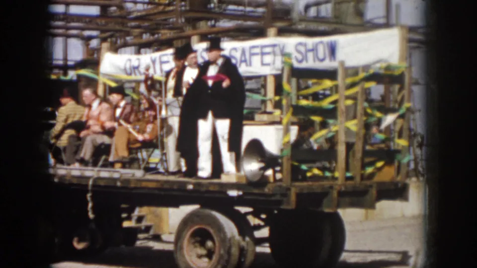 1958 Virginia parade footage showing a flatbed truck with seated people, costumed entertainers, bunting, and a SAFETY SHOW banner.