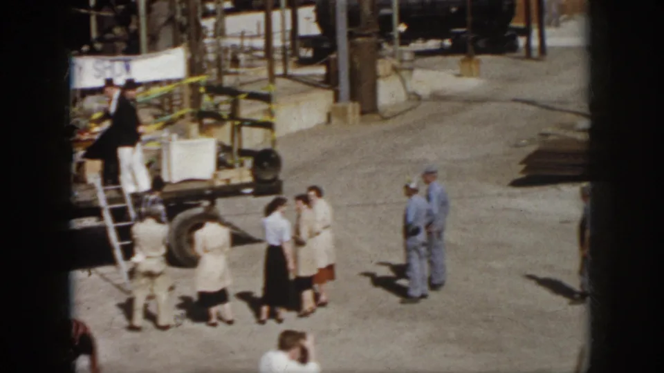 1958 Virginia home-movie frame with a wider view of the safety show truck stage and workers watching from the industrial yard.
