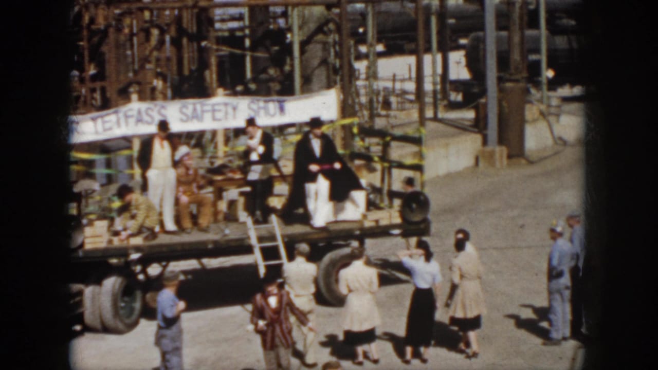 1958 Virginia frame with suited performers on a flatbed truck stage, spectators nearby, and a Dr. Tefas safety banner across the back.