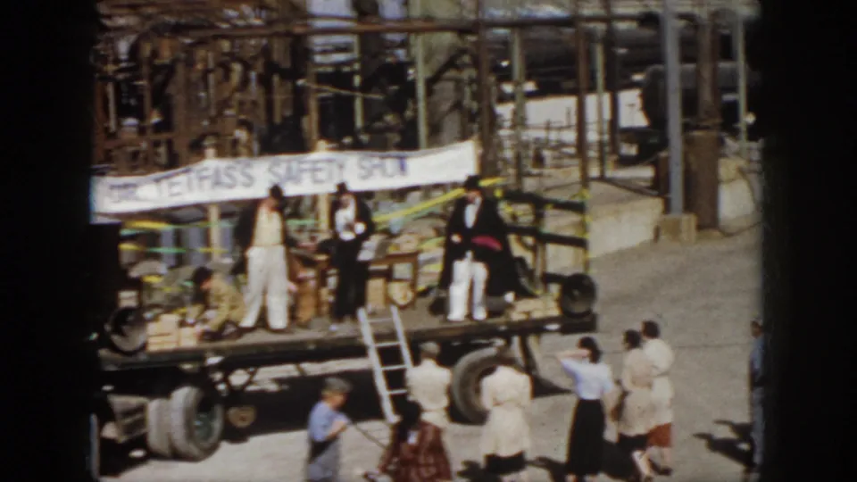 1958 Virginia home-movie view of the safety show truck stage as people stand below and industrial piping fills the background.