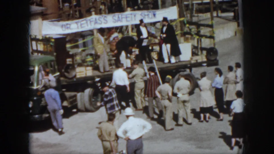 Home-movie frame from 1958 Virginia showing a safety-show stage on a truck with a watching crowd.