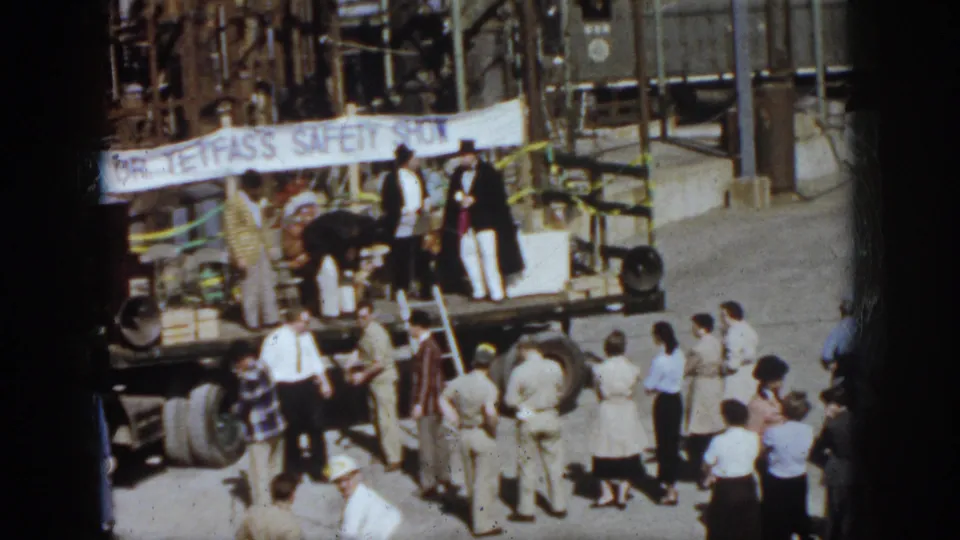 1958 Virginia safety-show gathering with spectators clustered near a flatbed truck stage and banner.