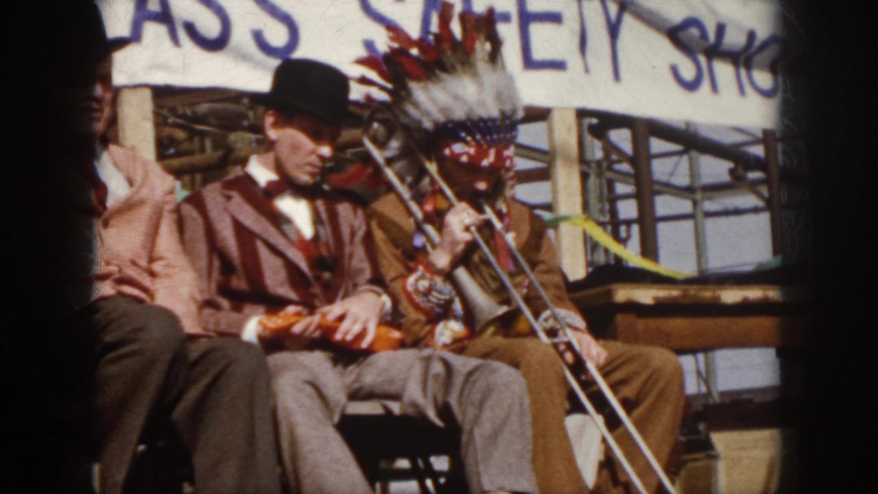 1958 Virginia frame showing the seated violin and trombone act on an outdoor stage with banner lettering and ribbon decoration.