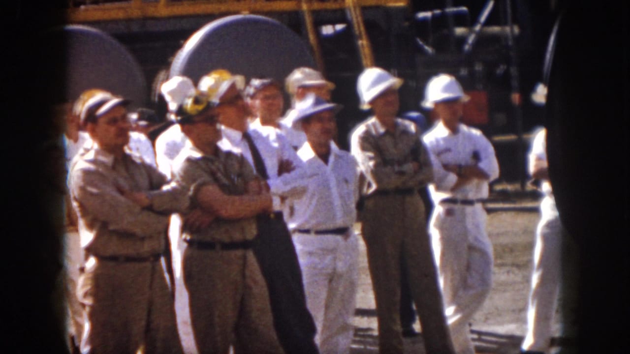 Virginia 1958 industrial meeting footage showing men in hard hats and coveralls gathered near a large loudspeaker.