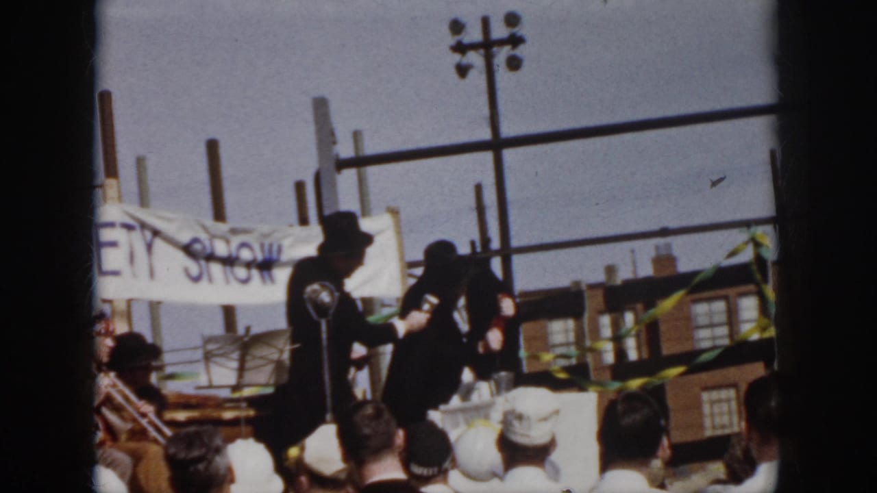 A caped man in a top hat holds a microphone while another costumed performer gestures during the 1958 Virginia outdoor variety show.