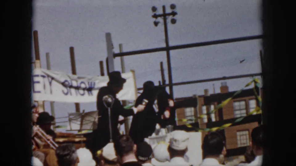 A caped man in a top hat holds a microphone while another costumed performer gestures during the 1958 Virginia outdoor variety show.