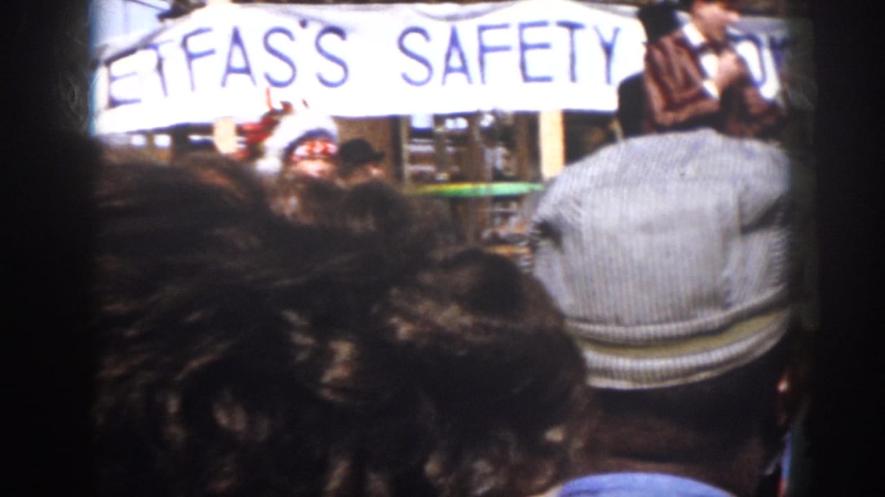Audience-view frame from Virginia 1958 showing spectators in the foreground and costumed safety-show performers on a small outdoor stage.