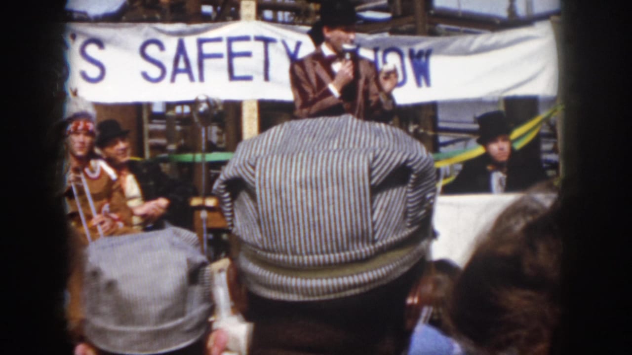 Virginia 1958 audience perspective with a striped cap in the foreground, seated costumed figures, and a safety-show banner across the stage.