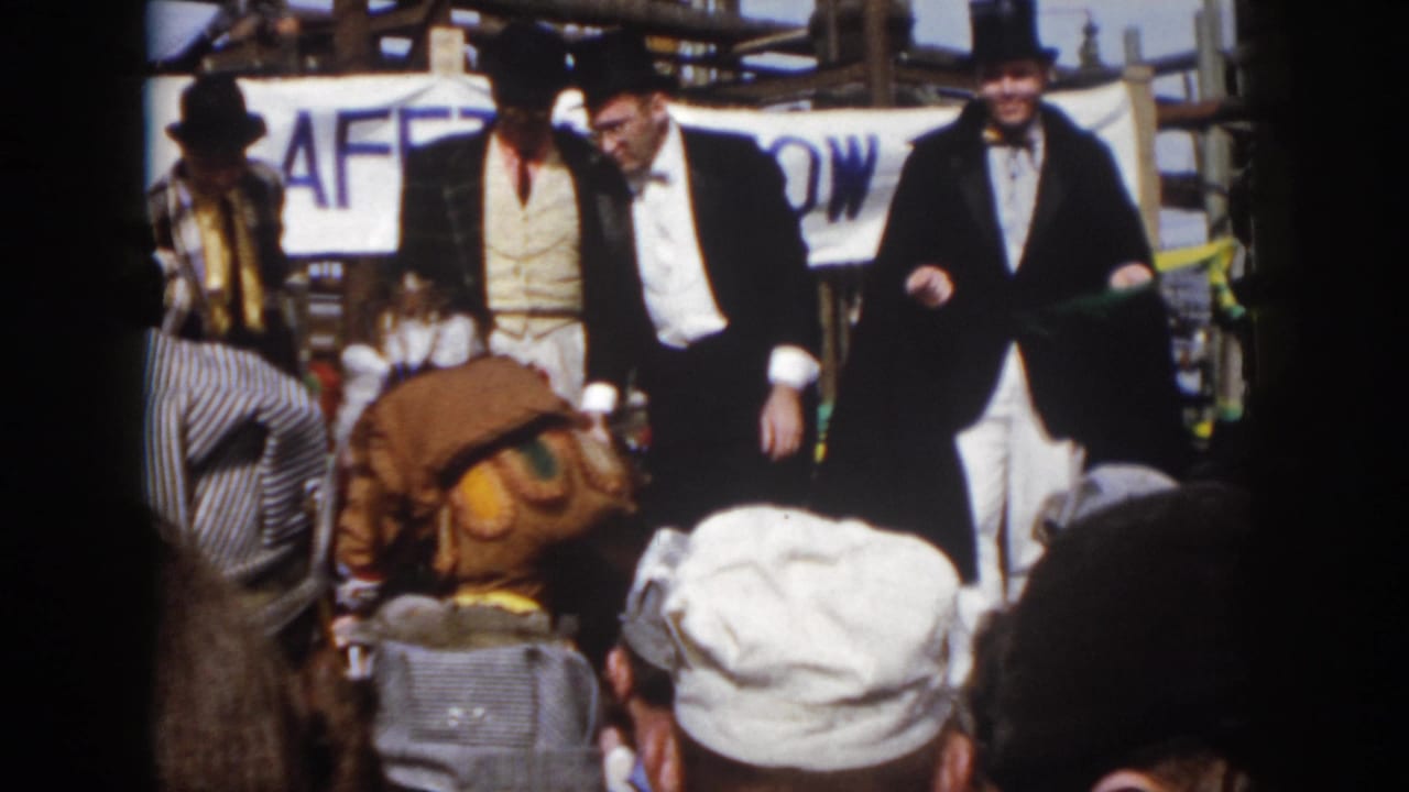 1958 Virginia safety-show frame with tuxedoed performers, a bending man in Native American regalia, spectators, and industrial structures.