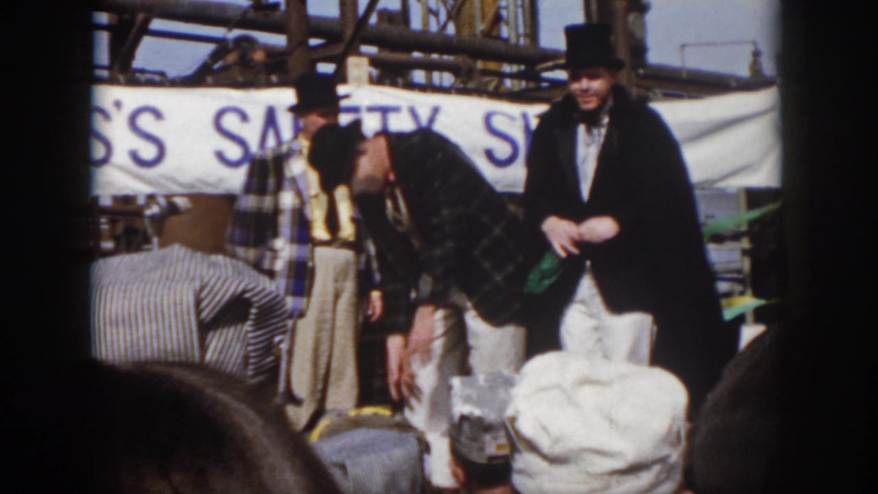 1958 Virginia home-movie frame showing one performer bending down while two costumed men stand nearby during the safety show.