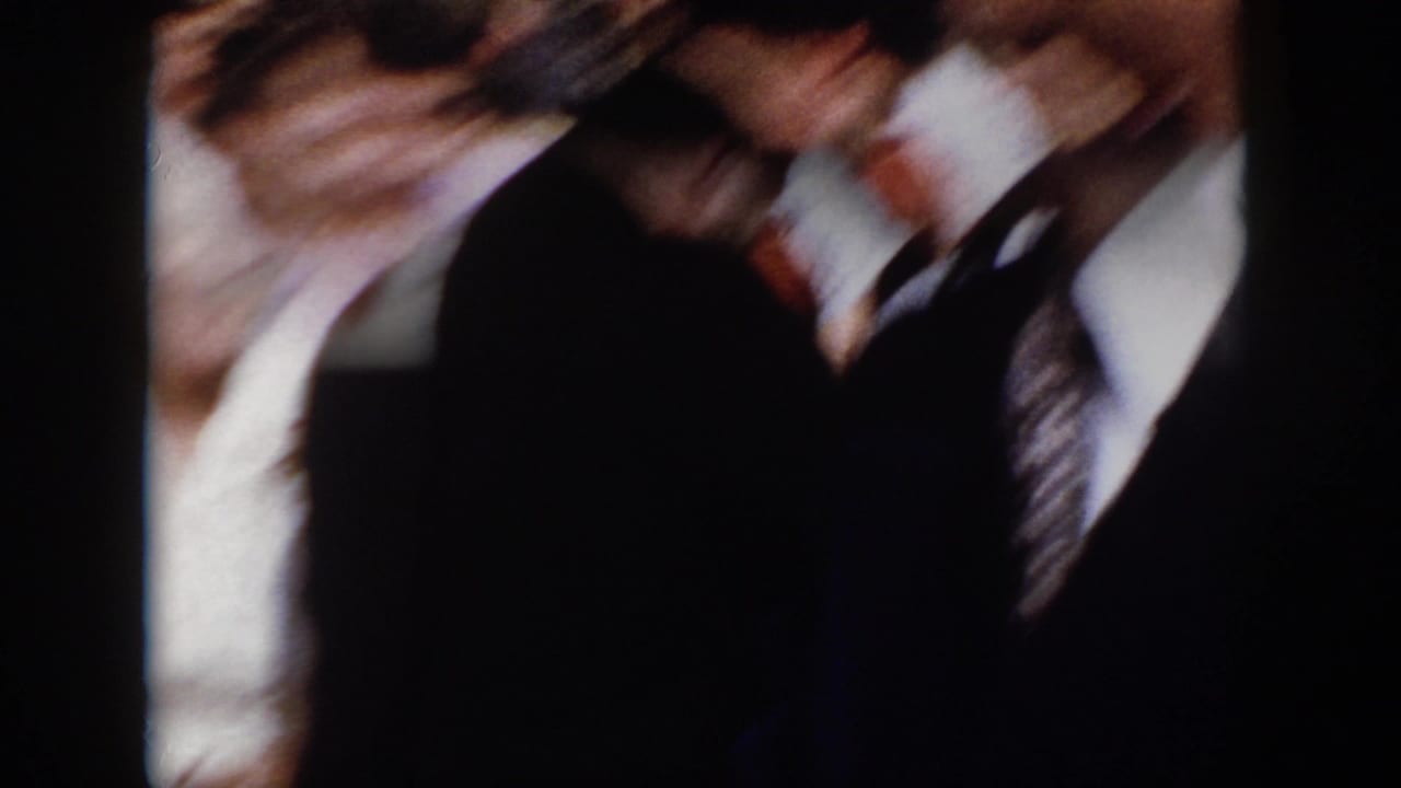 A handheld 8mm frame from the 1958 Virginia event is largely obscured by blurred people passing close to the camera.
