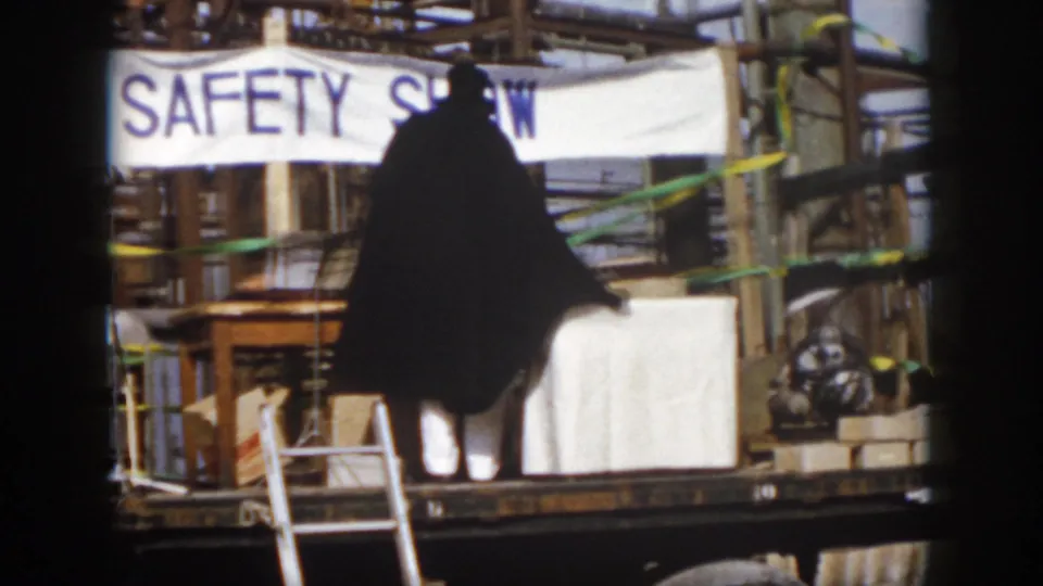 The safety show platform appears with a caped figure, ladders, white panels, and industrial equipment in the Virginia trade fair setting.