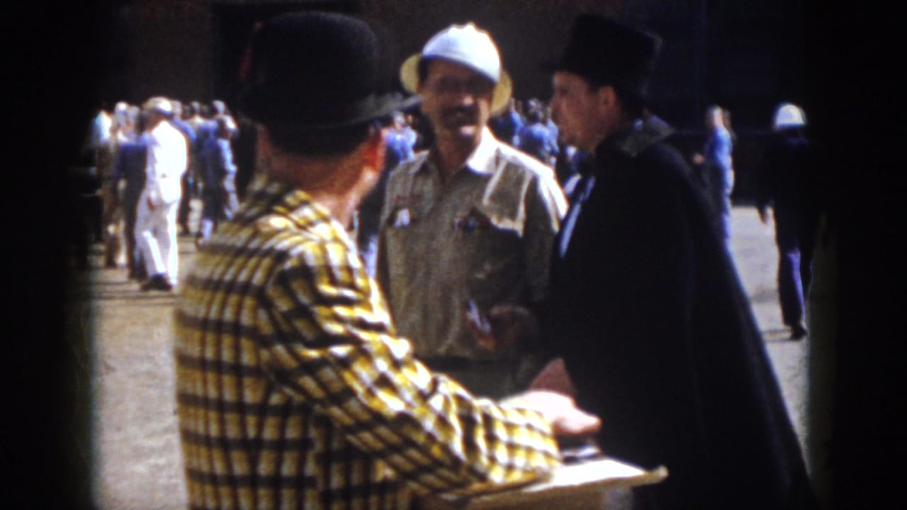 1958 Virginia frame with a plaid-shirted man near a man in a white safari-style hat and another in a black top hat and cape.