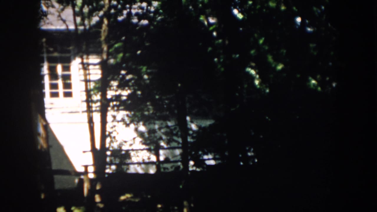 A final 1958 Virginia frame shows the house exterior still obscured by trees, with strong contrast between shade and sunlit siding.