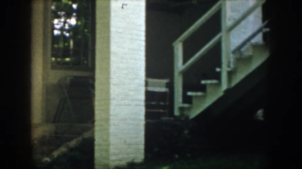 White brick pillar, exterior stairs, railings, and shaded lodging details appear in this 1958 Virginia 8mm frame.
