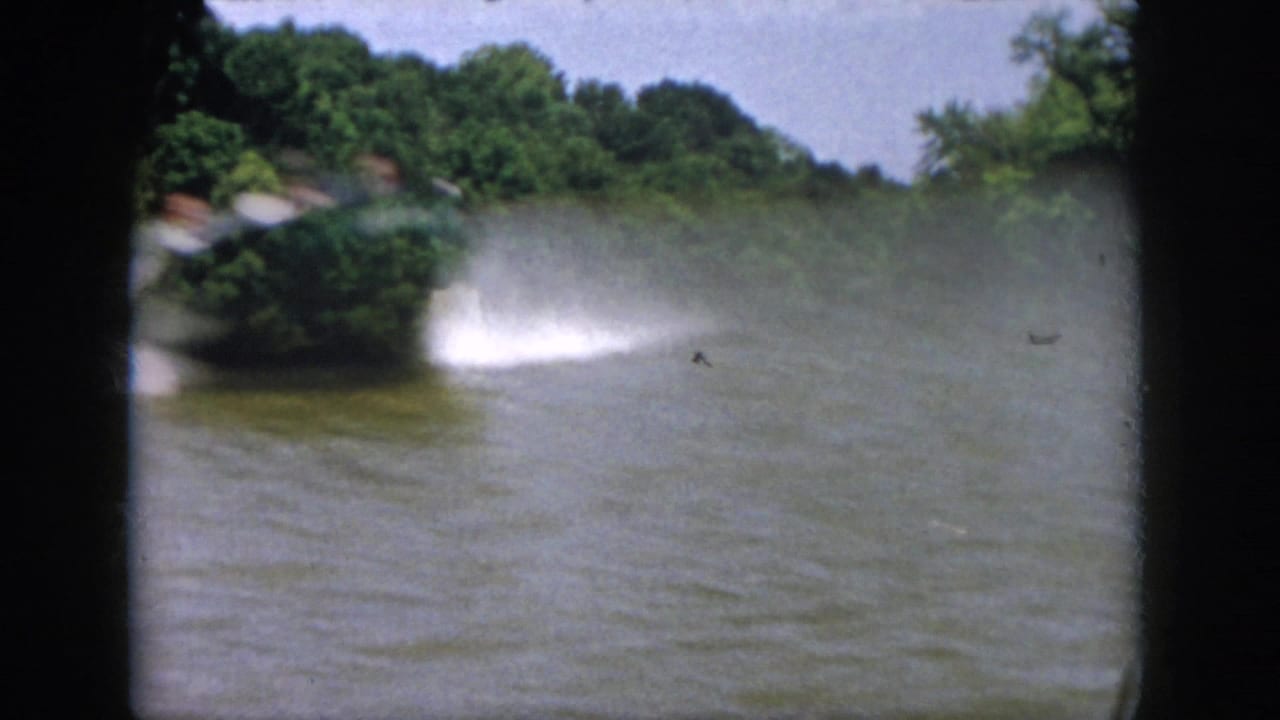 Fast-moving motorboat passes close to the camera on a Virginia lake, creating heavy spray in the 1958 home-movie footage.