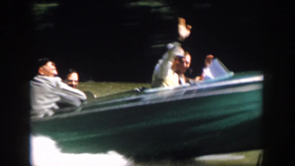Close 1958 Virginia home-movie view of adults riding in a green motorboat, including a man raising his hand toward the camera.