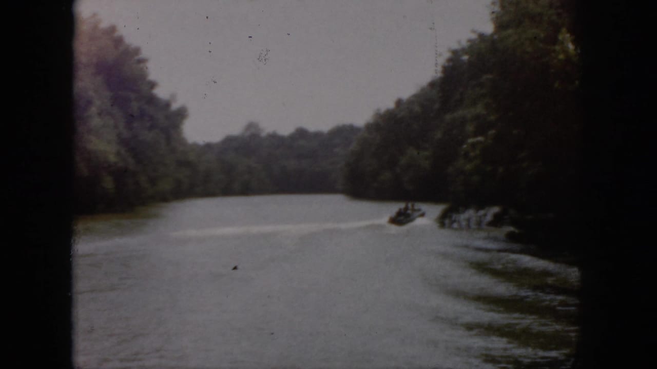 1958 Virginia 8mm home-movie frame showing a wooded river with soft focus, faded color, and dark film edges.