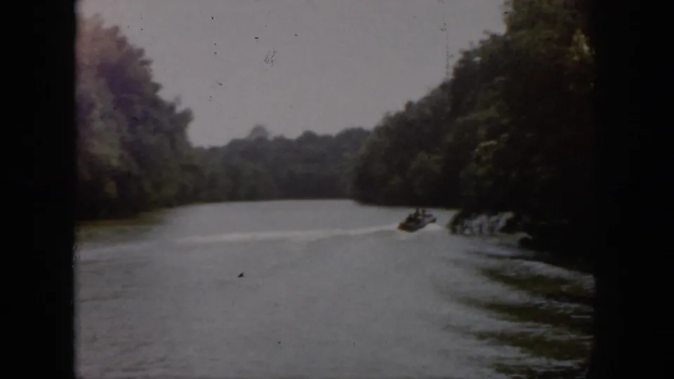 1958 Virginia 8mm home-movie frame showing a wooded river with soft focus, faded color, and dark film edges.