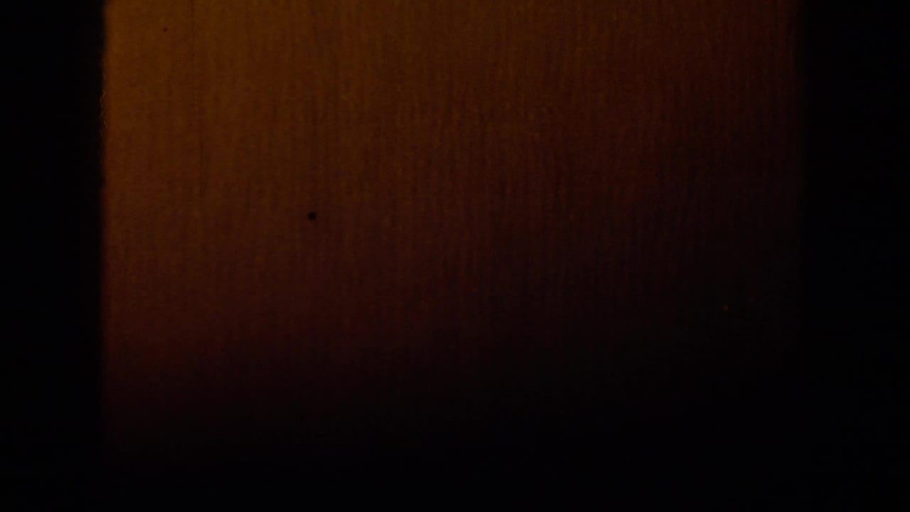 Dark transitional 8mm frame with a warm brown exposed strip and little visible scene detail.