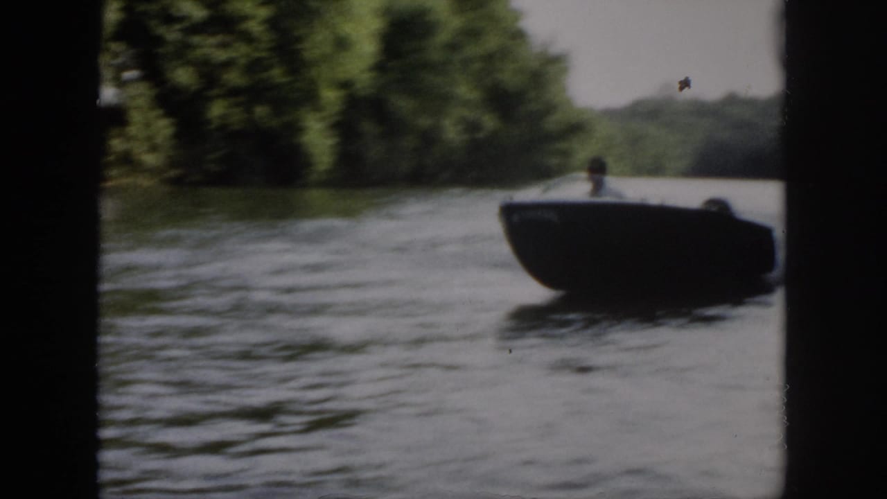 The boat comes toward the camera on a wooded Virginia river, with the driver faintly visible against soft 8mm exposure.