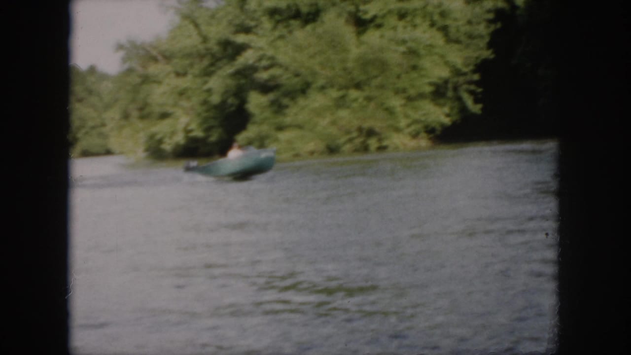 A green motorboat passes along a wooded Virginia river in soft 1958 8mm home-movie footage.