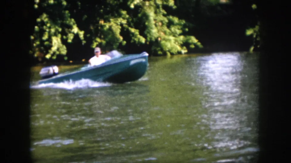 The motorboat travels through a shaded Virginia river scene, with the driver visible behind a small windshield.
