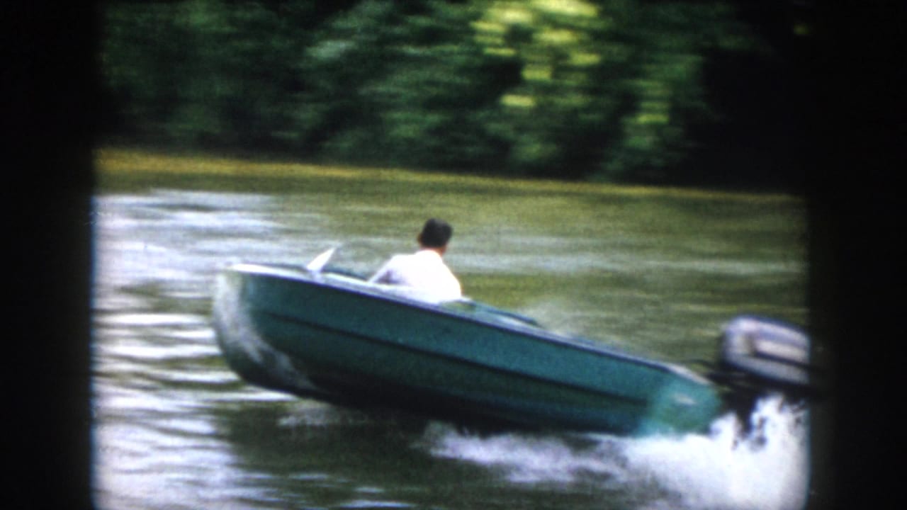 Closer 1958 Virginia home-movie view of a blue speedboat turning, with an outboard motor and wake visible.