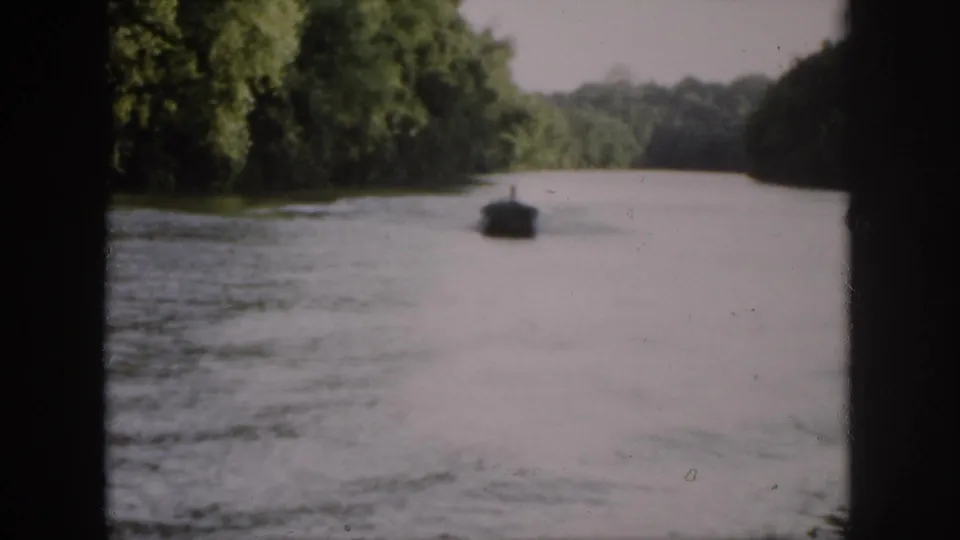 A wider 1958 Virginia river view shows the boat receding down the channel between tree-lined banks.