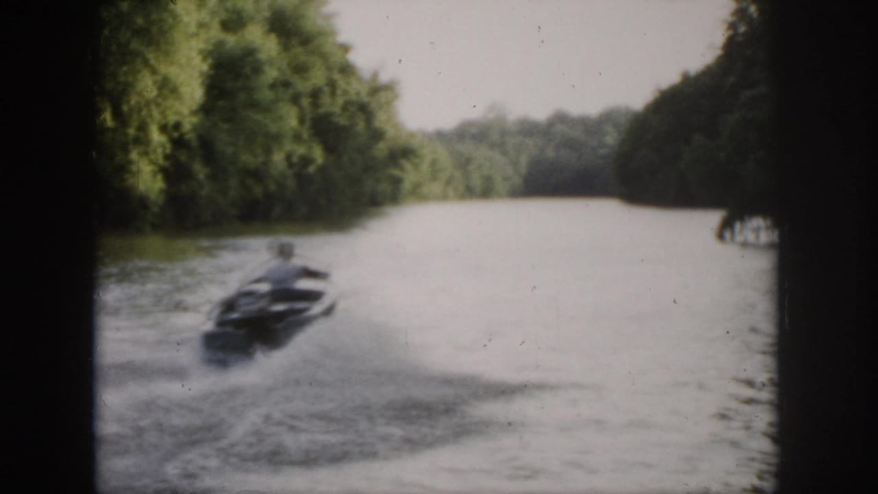 The speedboat moves away along a wooded Virginia river, leaving a visible wake in soft 1958 home-movie footage.