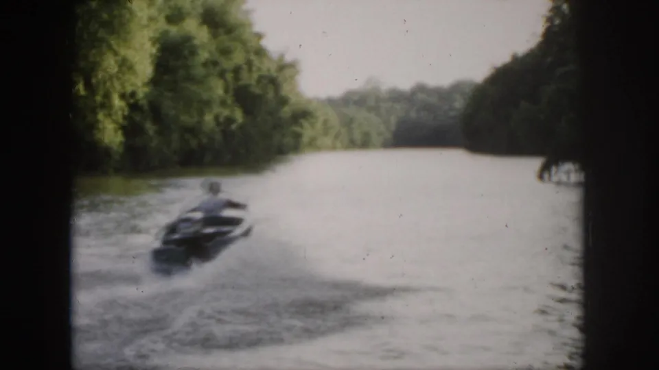 The speedboat moves away along a wooded Virginia river, leaving a visible wake in soft 1958 home-movie footage.