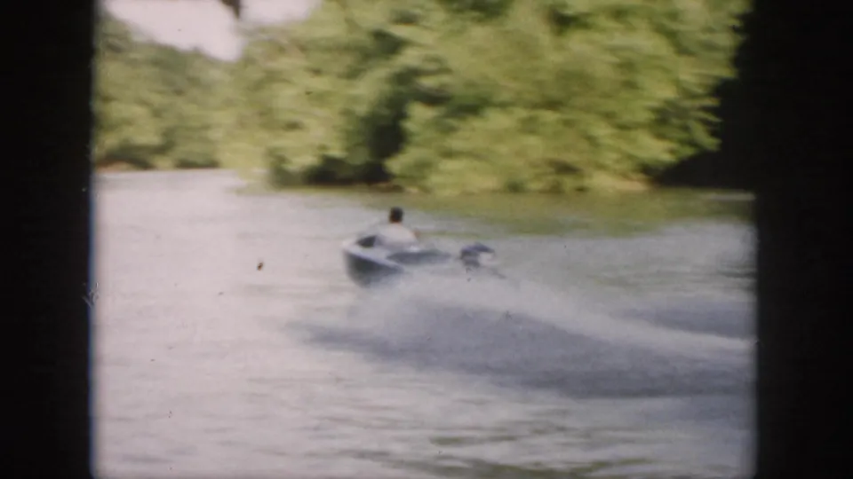The speedboat races away across a wooded Virginia waterway, trailing a wide spray wake in 1958 8mm footage.