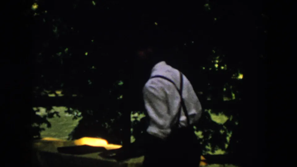 In 1958 Virginia home-movie footage, an adult man in suspenders is seen from behind near a dark wooded waterfront.