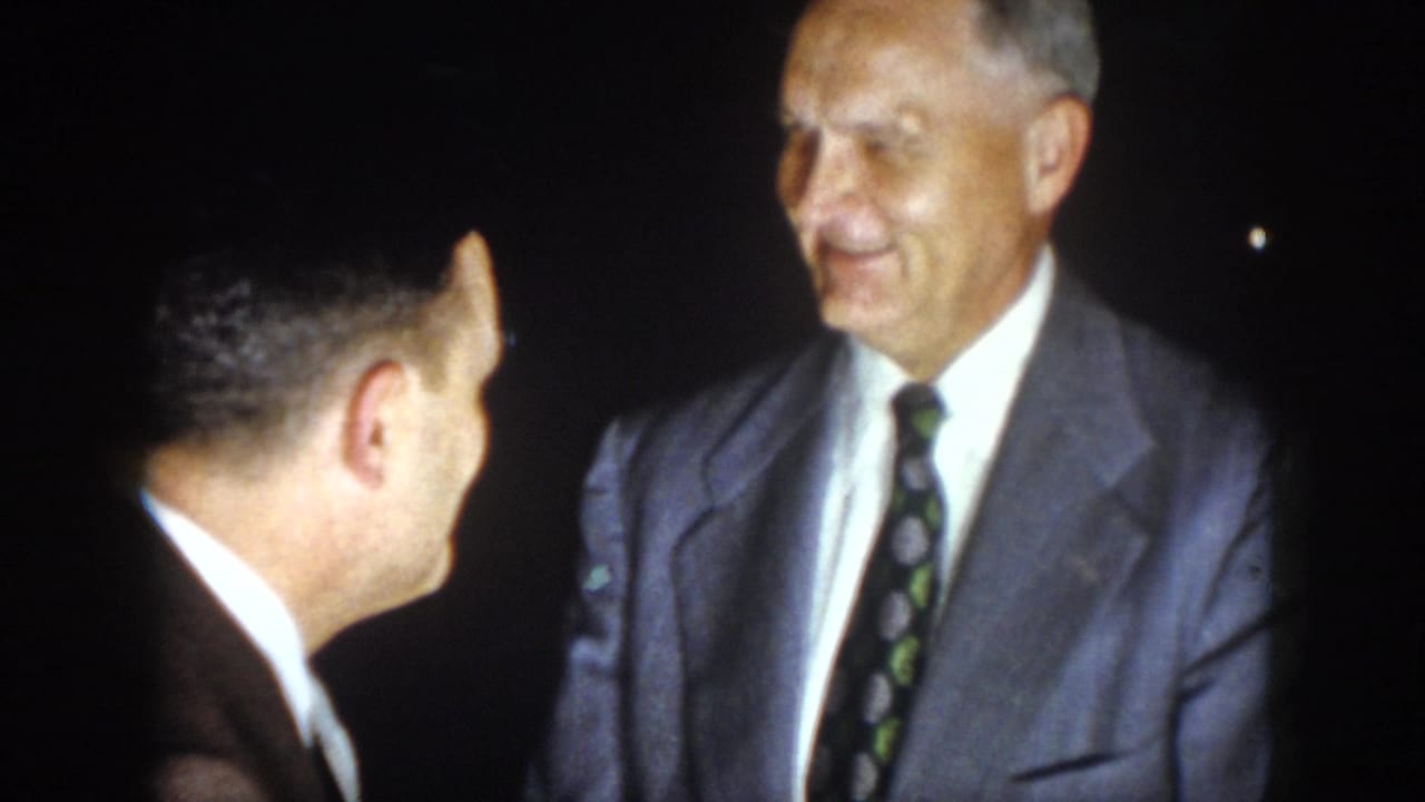 In 1958 Virginia home-movie footage, two adult men in suits face each other during a nighttime conversation.
