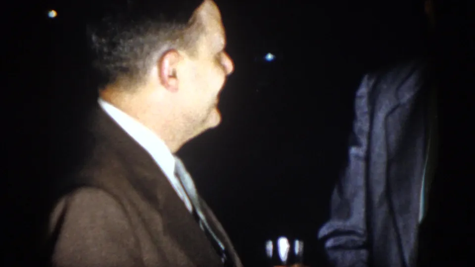 At the end of the 1958 Virginia clip, the bow-tied man turns toward the other suited man in the dark setting.