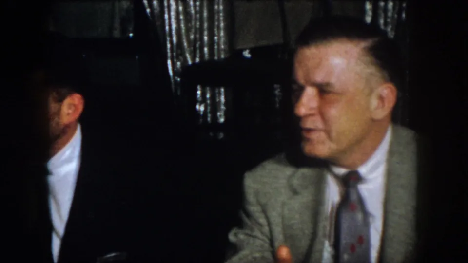 Virginia 1958 frame showing suited men seated in a dim private interior, one partly obscured by shadow.