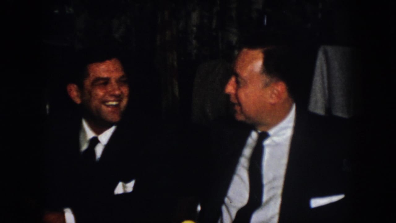 At the end of the 1958 Virginia banquet clip, two suited men turn toward each other in conversation and laughter.