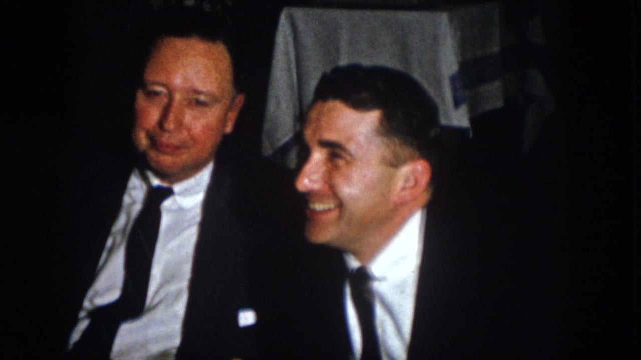 At the Virginia banquet, two men in formal suits sit close together as one smiles broadly.
