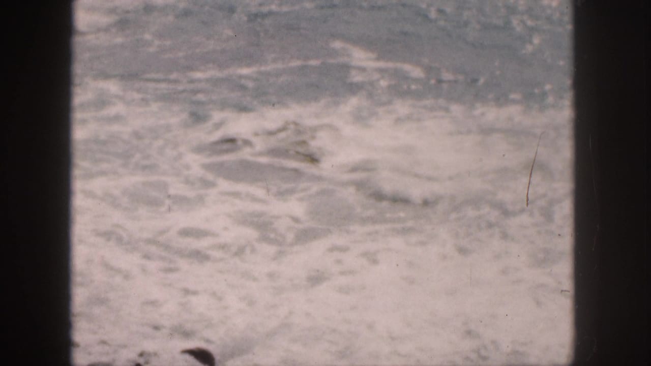 Foamy ocean water seen beside dark vertical frame edges.