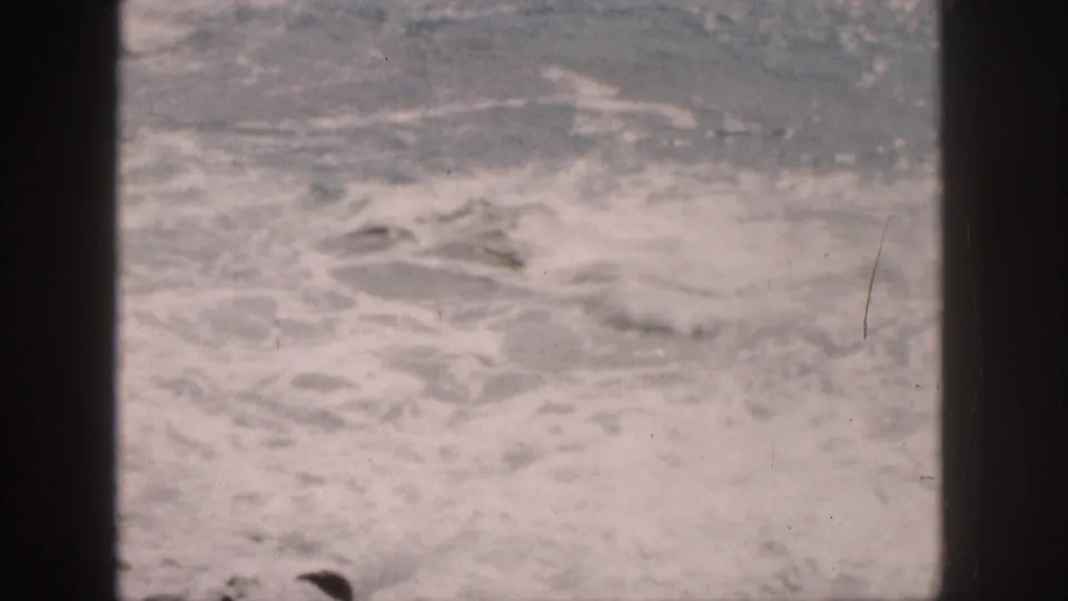 1959 Hawaii shoreline footage showing turbulent foamy water bordered by dark frame elements.