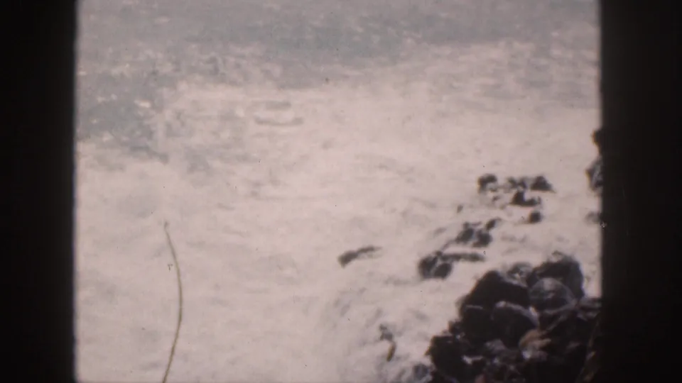 1959 Hawaii coastal view with foamy waves breaking near dark rocks and a vertical frame edge.