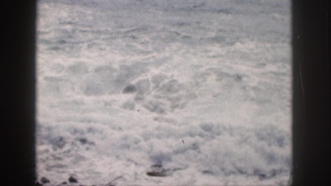 Foaming waves churn behind dark vertical frame edges.