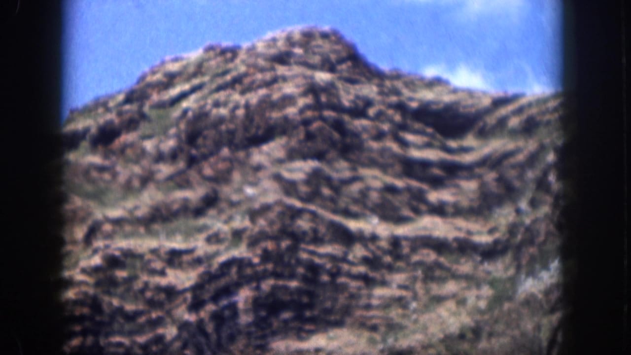 1959 Hawaii home-movie view of a rugged rocky hill rising beneath a clear blue sky.